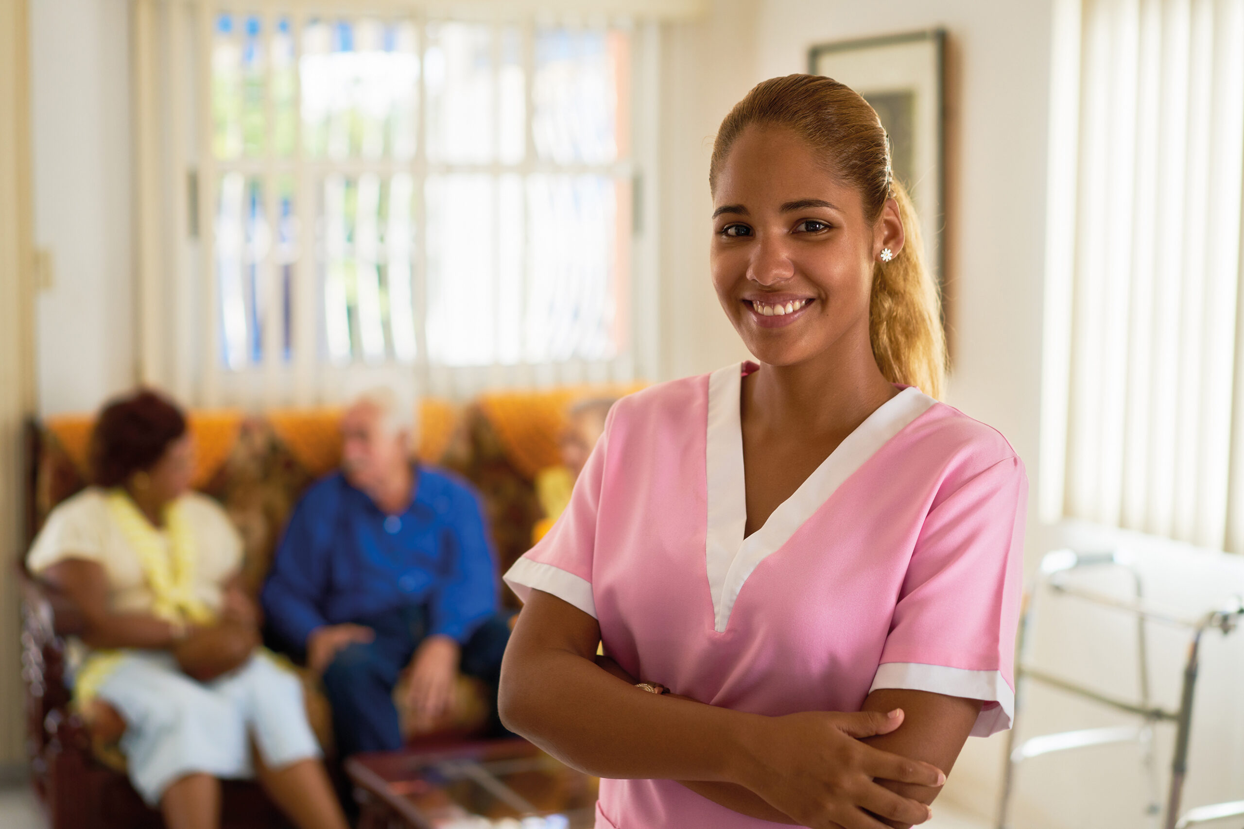 Portrait of girl at work as nurse in medical clinic for seniors. Happy worker smiling at camera in hospice.